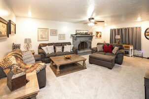 A living room with a fireplace, multiple sofas, a coffee table, and a ceiling fan.