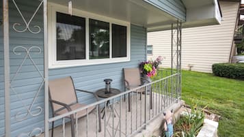A porch with two chairs, a small table, and a potted plant.