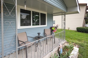 A porch with two chairs, a small table, and a potted plant.