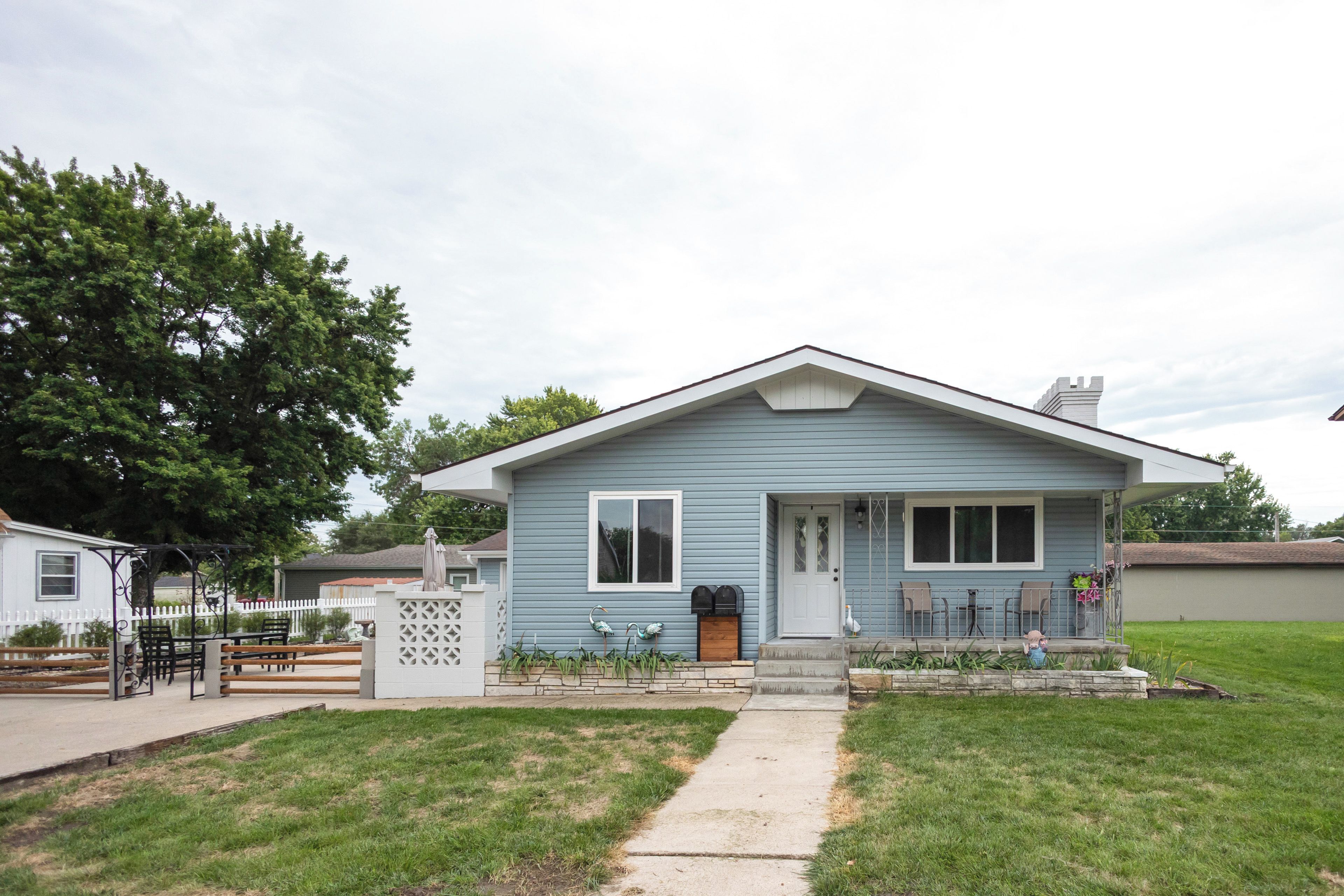 A single-story house with a front porch, a mailbox, and a small garden area.