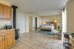 Una habitación de hotel con cama, mesita de noche, lámpara y una kitchenette con tostadora.