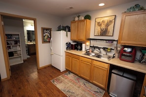 A compact kitchen with wooden cabinets, a white refrigerator, a coffee maker, and a small oven.