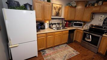 A kitchen with wooden cabinets, a refrigerator, a microwave, a stove, and a coffee maker.