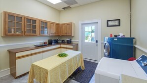 Una cocina compacta con armarios de madera, microondas, cafetera y lavadora.