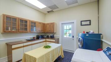 A compact kitchen with wooden cabinets, a microwave, a coffee maker, and a washing machine.
