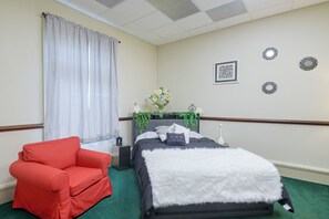 Une chambre d’hôtel avec un lit, un fauteuil rouge, une table de chevet et des miroirs décoratifs sur les murs.