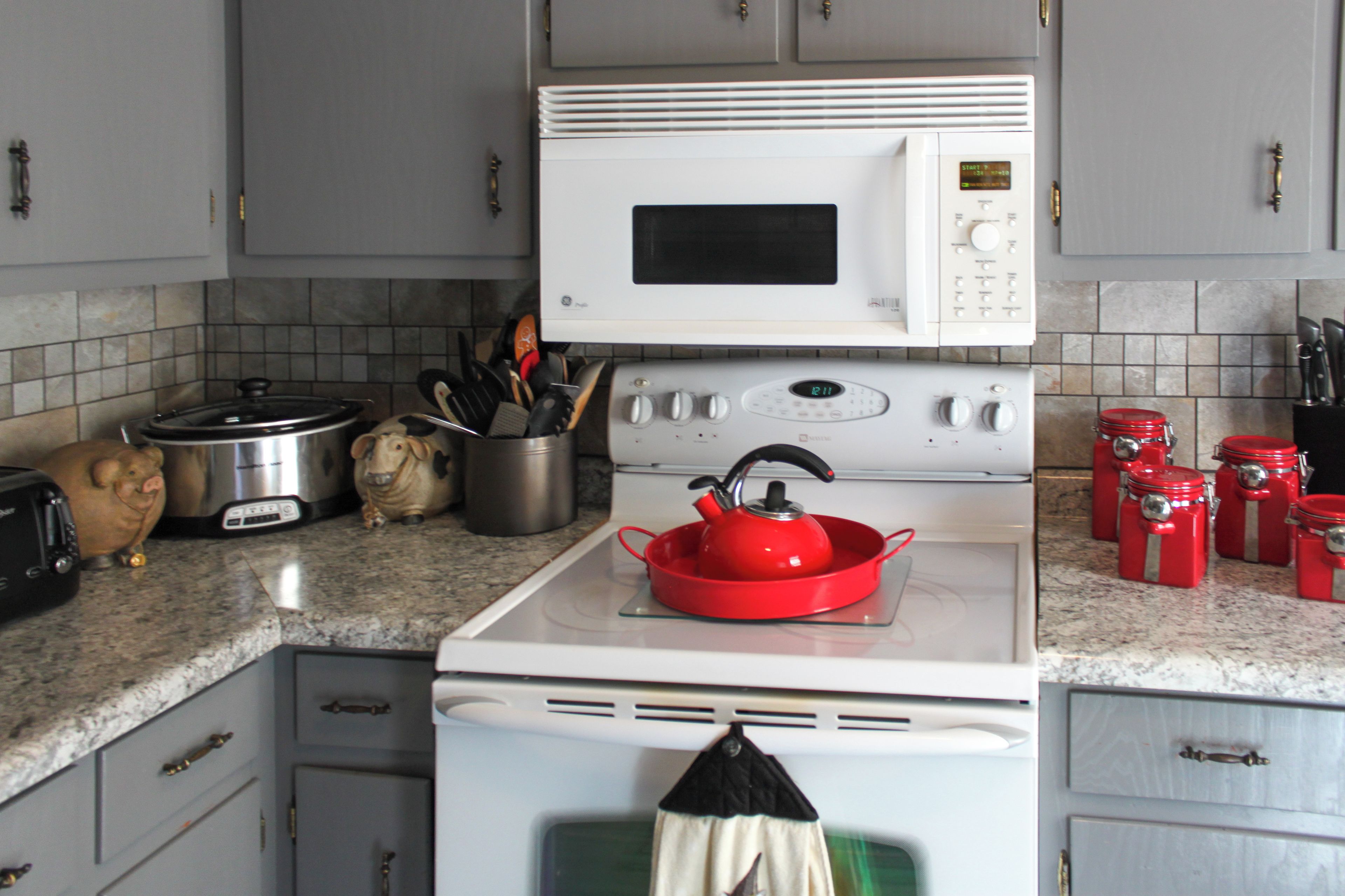 Uma cozinha equipada com micro-ondas, fogão e diversos utensílios.