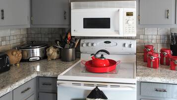 Uma cozinha equipada com micro-ondas, fogão e diversos utensílios.