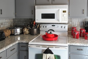 Une cuisine équipée d’un four à micro-ondes, d’une cuisinière et de divers ustensiles de cuisine.