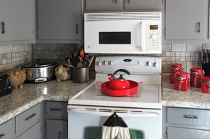 A kitchen with a microwave, stove, and various kitchen utensils.