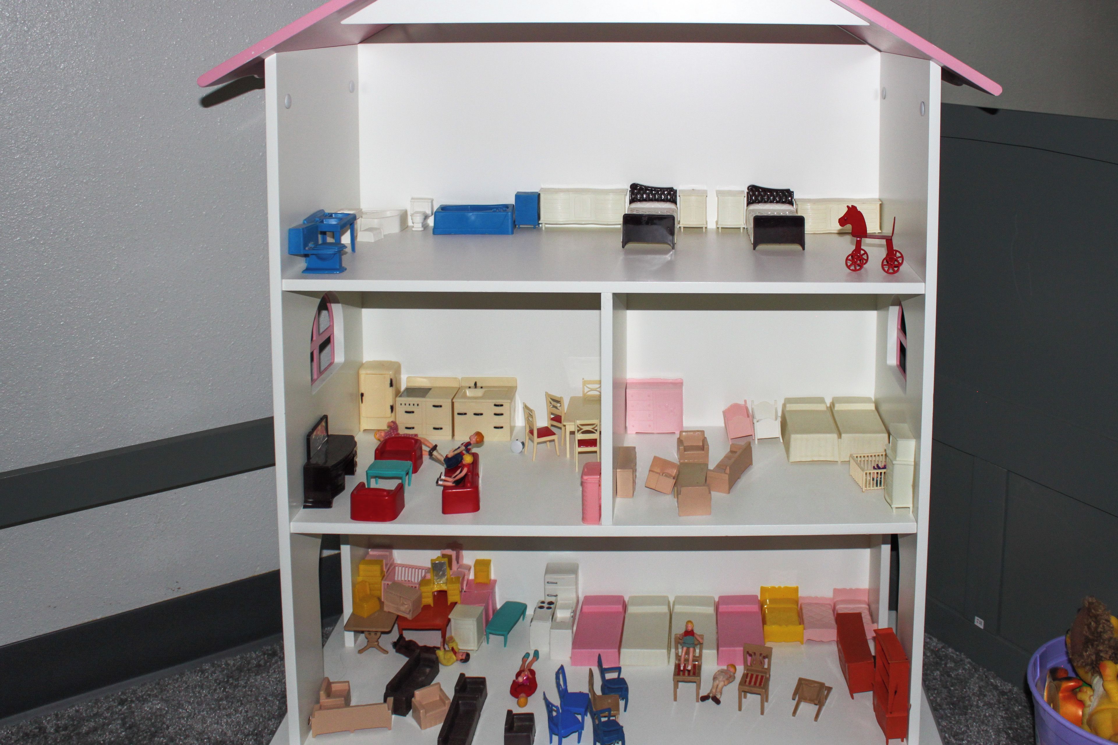 A dollhouse with multiple rooms, including a kitchen, living room, and bedrooms.