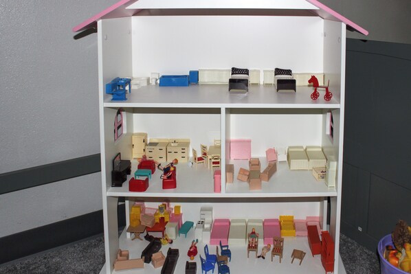 A dollhouse with multiple rooms, including a kitchen, living room, and bedrooms.