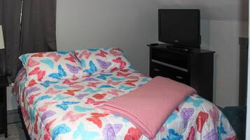 A bedroom with a bed, a television on a stand, and a dresser.