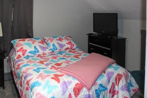 Un dormitorio con cama, televisor sobre un mueble bajo y cómoda.