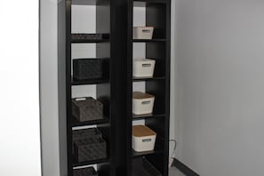 Une étagère noire avec plusieurs compartiments de rangement, placée contre un mur.