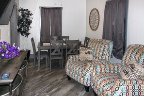 A compact living space with a dining table, chairs, a sofa, and a decorative wall piece.
