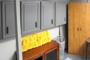 Una habitación con armarios grises, un banco de madera y una cesta de ropa.