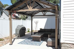 A covered patio area with a grill, seating, and a decorative rug. - The Hide Out - a Family Getaway in Columbus (Columbus)
