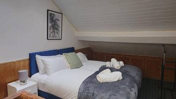 A bedroom with a bed, pillows, a nightstand, a lamp, and a framed picture on the wall.