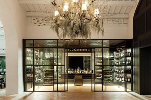 A bar with a large chandelier and glass display cases filled with bottles. - Mas De Torrent (Torrent)