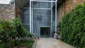 A modern building with a glass facade, stone exterior walls, and a landscaped courtyard. - Mana Hotel Ranakpur (Desuri)