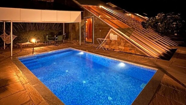 A swimming pool with a stone deck, a covered seating area, and a staircase leading to an upper level. - Mana Hotel Ranakpur (Desuri)