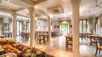 Un comedor amplio con varias mesas y sillas, un bufé con diversas opciones de comida, y vistas a través de las ventanas.