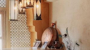 A wooden desk with a laptop, a lamp, and decorative items including a vase and framed pictures. - Rawla Narlai Luxury Heritage Hotel (Desuri)