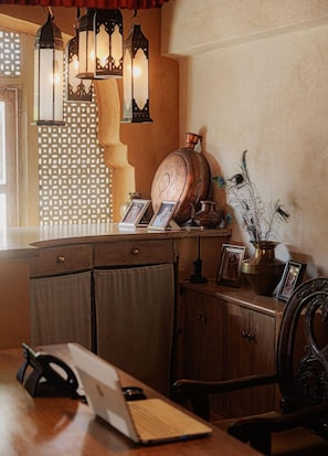 Un escritorio de madera con una computadora portátil, una lámpara y objetos decorativos, incluyendo un florero y marcos con fotografías.