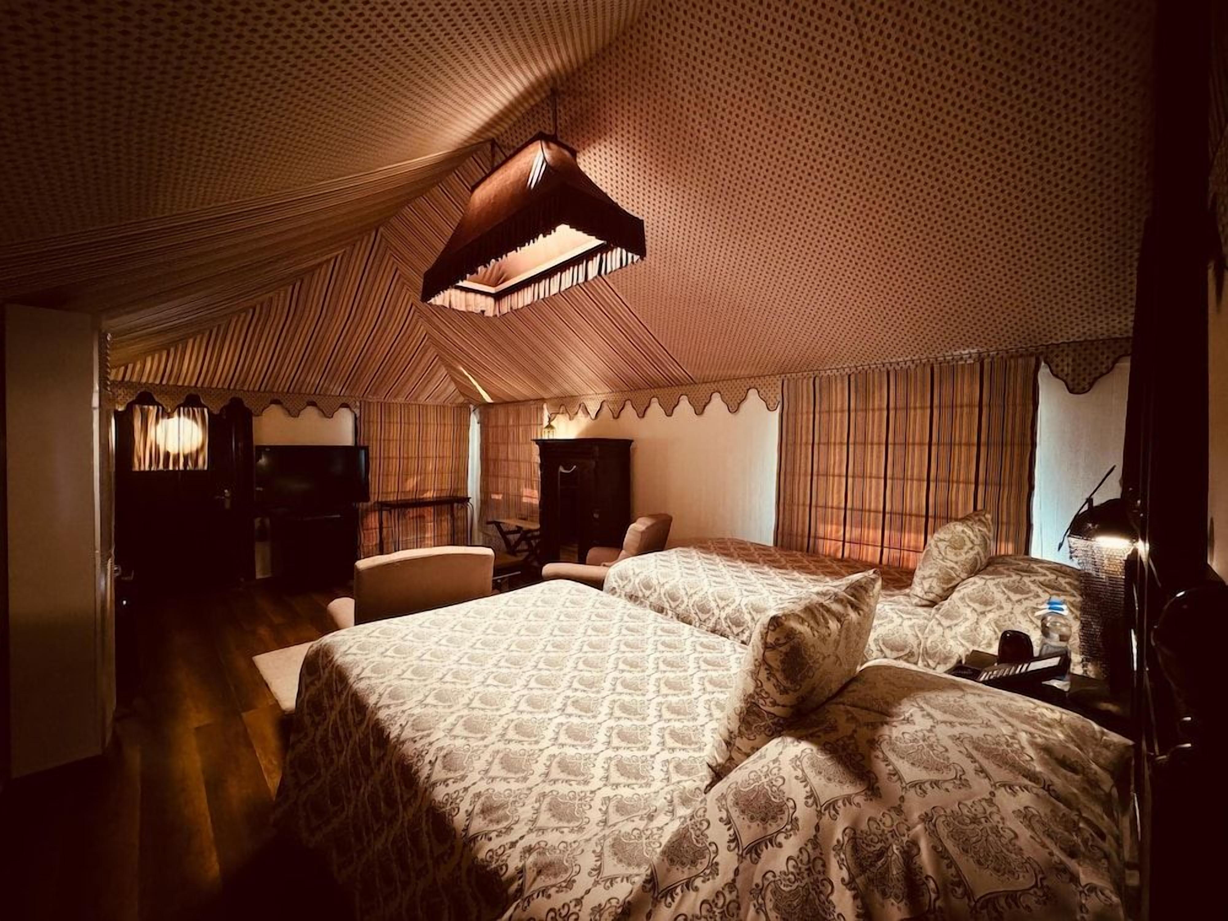 Una habitación con una colcha estampada, una lámpara colgante y un techo con diseño.