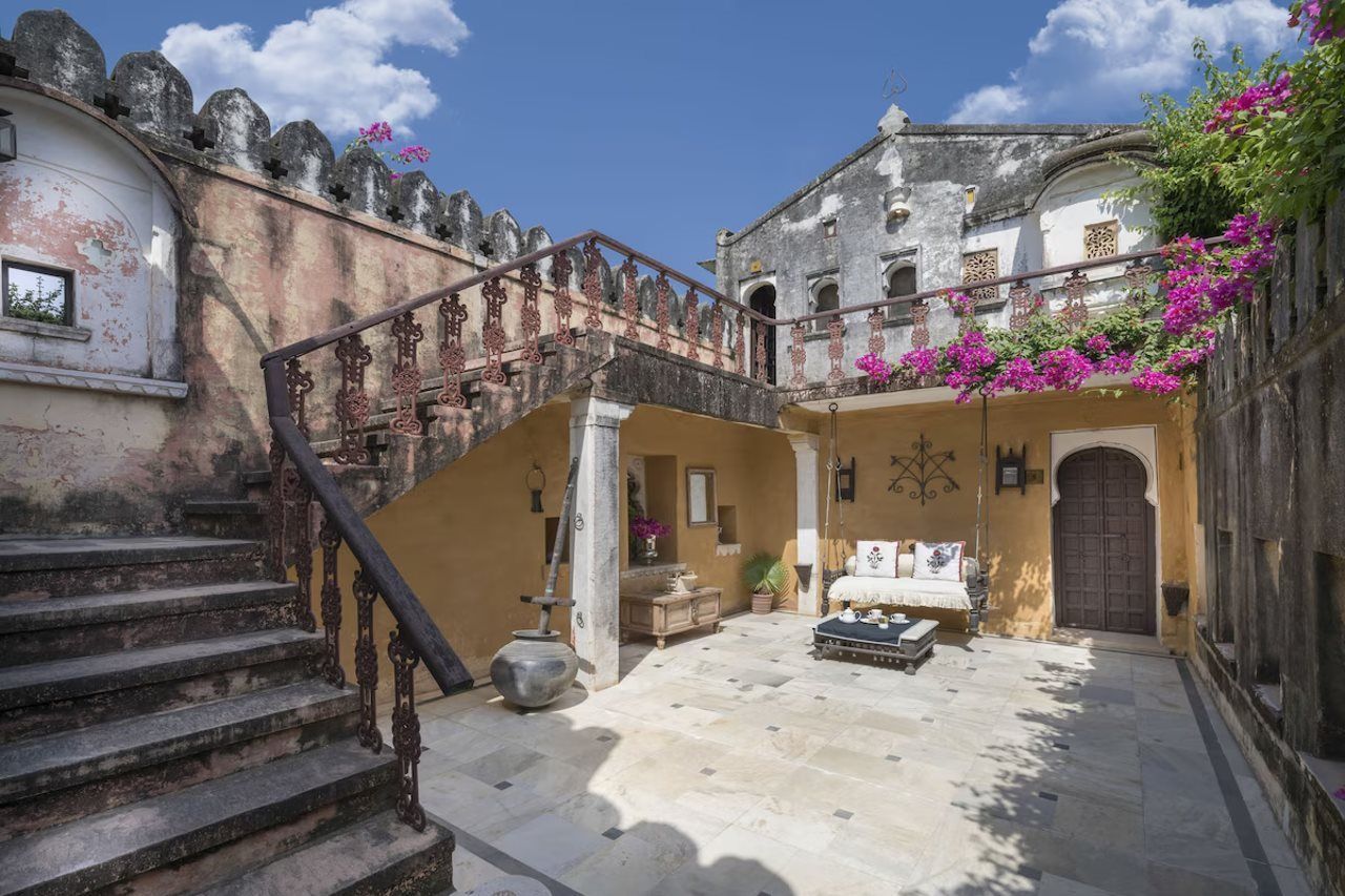Un patio con escalera, cama y puerta.