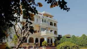 A multi-story building with a traditional architectural style, featuring arched windows and balconies. - Rawla Narlai Luxury Heritage Hotel (Desuri)