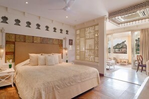 Un dormitorio amplio con una cama grande, una mesita de noche, un diseño decorativo en la pared y vistas a través de una ventana.