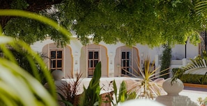 A courtyard with a white building featuring arched windows and a tiled floor.
