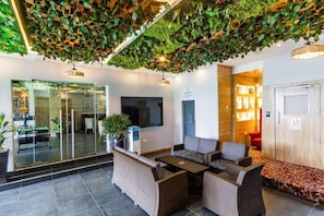 A lobby with a reception desk, seating area, and a wall-mounted television. - Bon Hotel Delta (Warri)