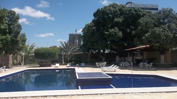 A swimming pool with lounge chairs and a building labeled 'Aguas Palace Hotel' in the background. - Hotel Grande Rio (Petrolina)
