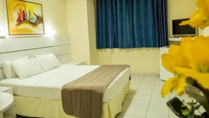 A hotel room with a bed, a desk, a television, and a window with curtains. - Hotel Grande Rio (Petrolina)