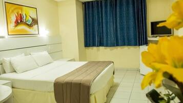 Een hotelkamer met een bed, een bureau, een televisie en een raam met gordijnen.