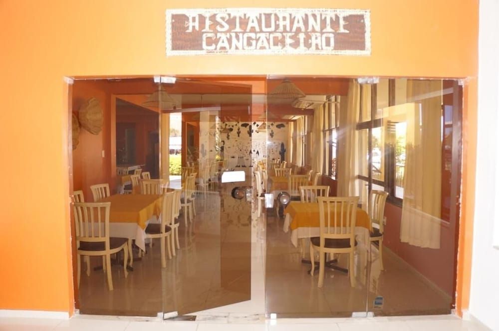 Restaurante com entrada espelhada, mesas e cadeiras de madeira.