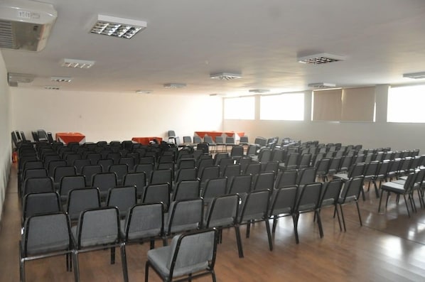 A conference room with rows of chairs, a podium, and a large window.