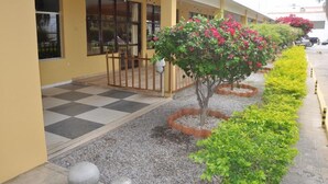 A building with a yellow exterior, a checkered floor, and a row of plants. - Hotel Grande Rio (Petrolina)