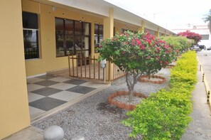 A building with a yellow exterior, a checkered floor, and a row of plants. - Hotel Grande Rio (Petrolina)