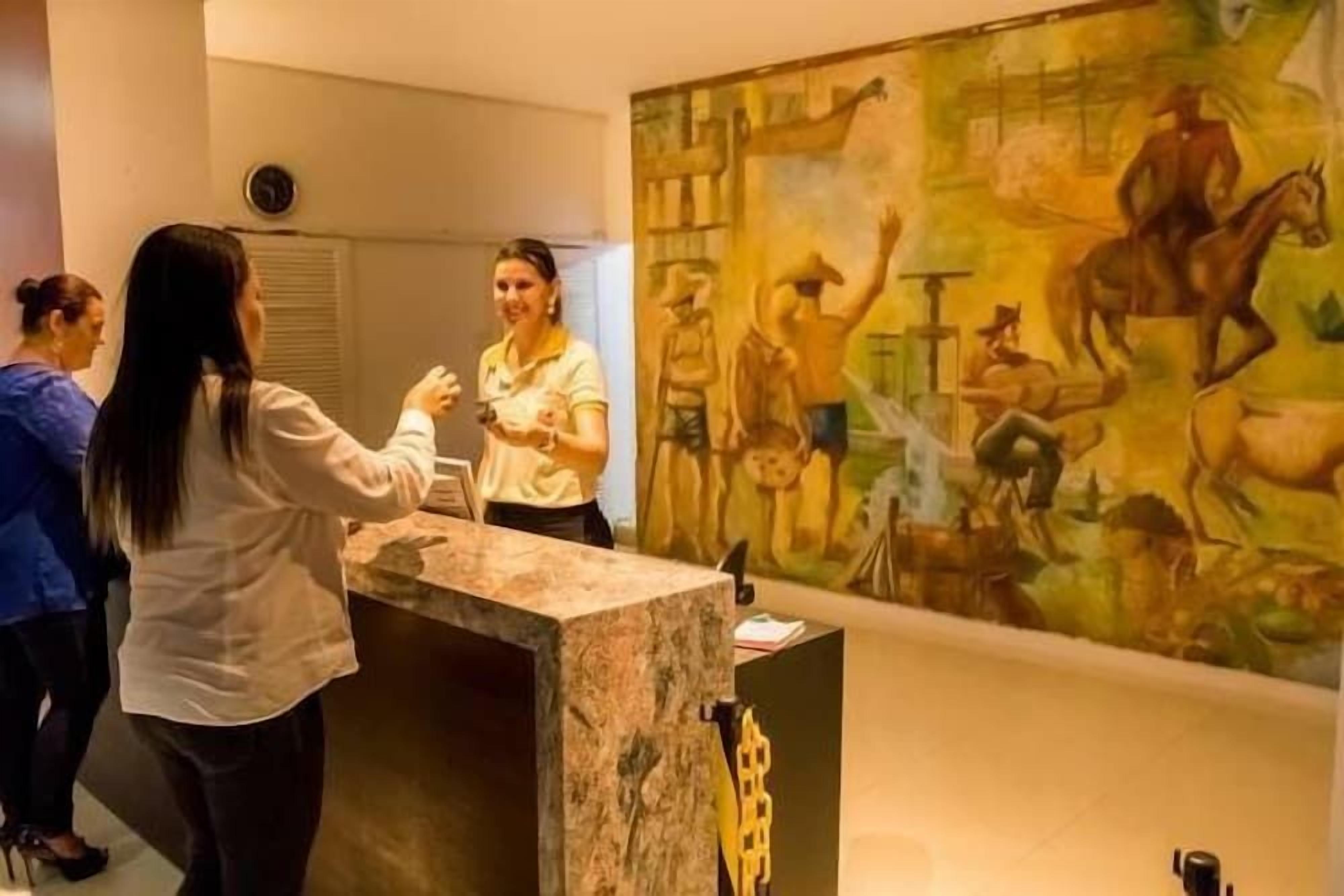 Una zona de recepción con mostrador de mármol, un cuadro grande en la pared y un reloj en la pared.