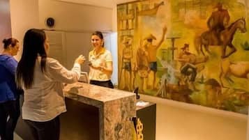 Una zona de recepción con mostrador de mármol, un cuadro grande en la pared y un reloj en la pared.