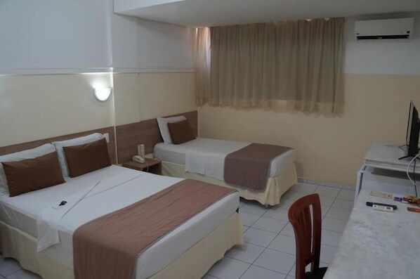 A hotel room with two beds, a desk, a chair, and an air conditioning unit. - Hotel Grande Rio (Petrolina)