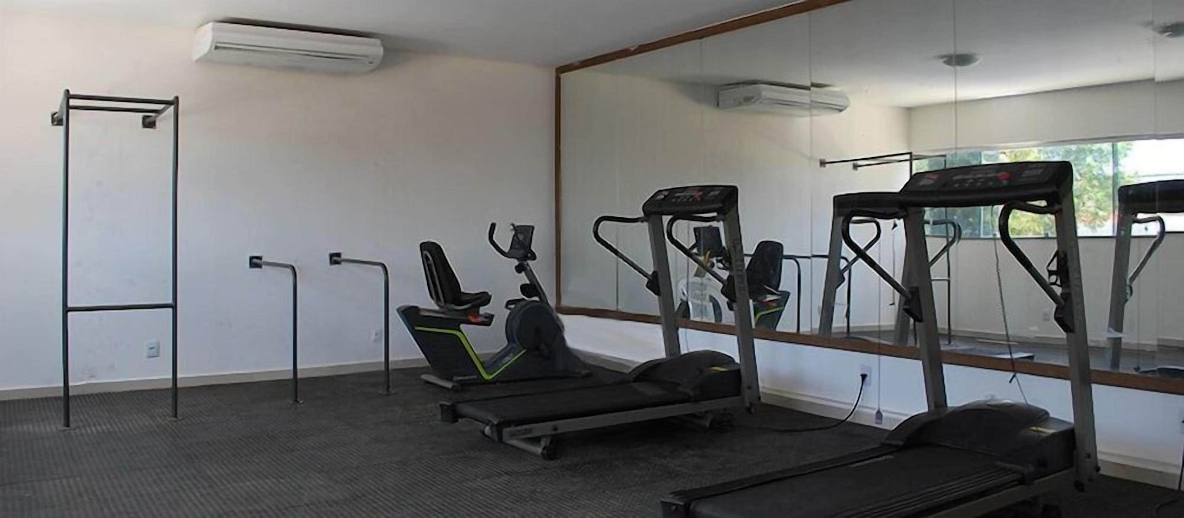 Een sportschool met loopbanden, een hometrainer en een optrekstang.