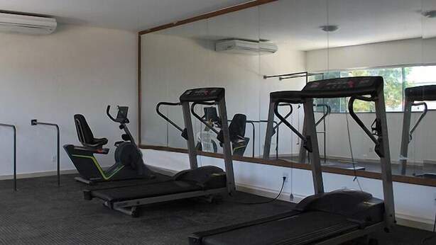 A gym with treadmills, a stationary bike, and a pull-up bar. - Hotel Grande Rio (Petrolina)
