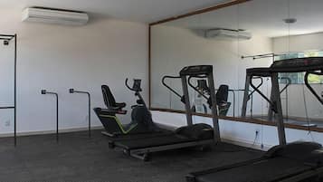Een sportschool met loopbanden, een hometrainer en een optrekstang.