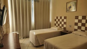 A hotel room with two beds, a desk, and a window with curtains. - Real Minas Suites Hotel (Governador Valadares)