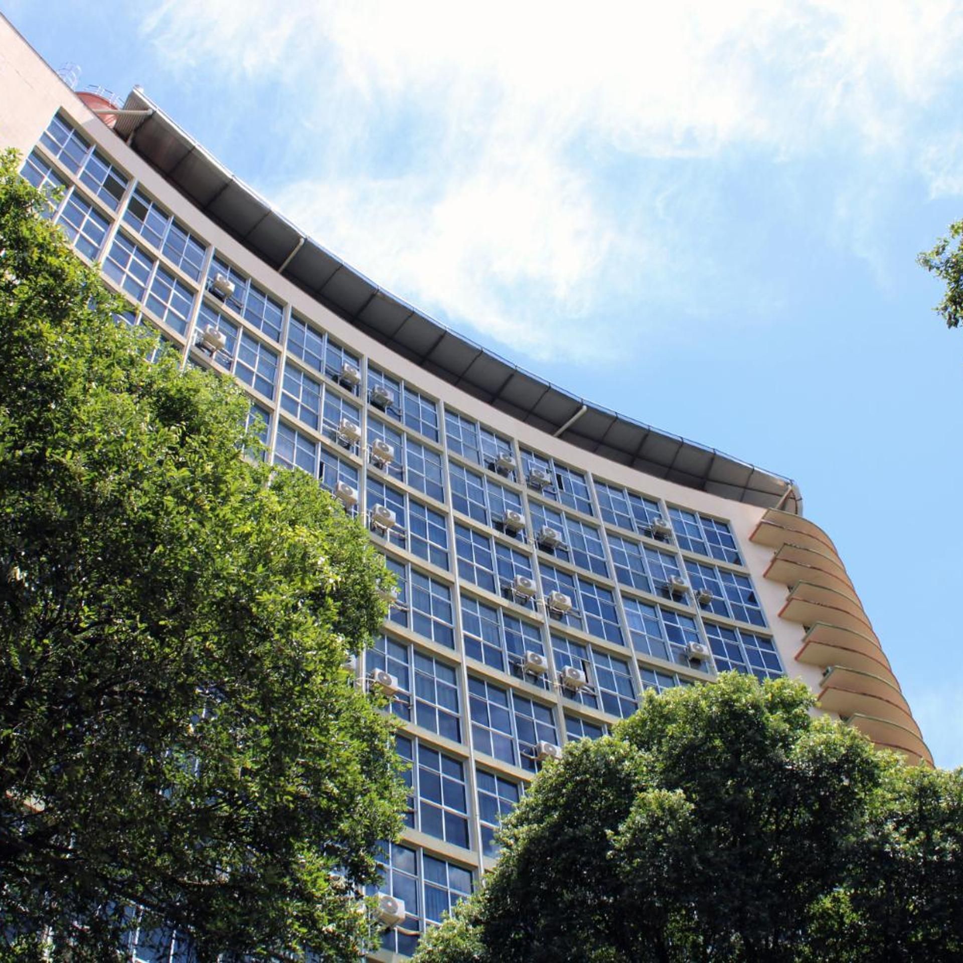 Um edifício moderno com fachada curva, janelas amplas e unidades de ar condicionado.